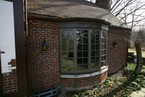 brown vinyl bay windows installed on front of brick home